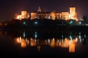 View from the river to the illuminated castle in Krakow