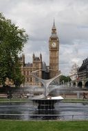 fountain in the square against the background of the big ben tower, uk, england, london