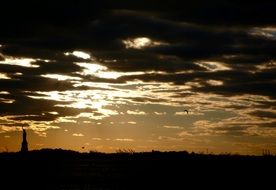 silhouette of the statue of liberty against the backdrop of a fiery sunset in New York