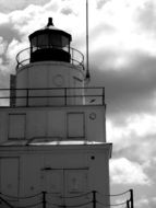 black and white photo of a lighthouse tower in the sea harbor