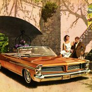 Couple Standing Next to Orange Convertible Car