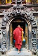 monk in a red robe entering the temple