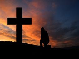 Photo of cross and human at the sunset