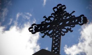 cemetery metal cross on the blue sky with white clouds