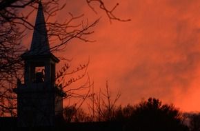 black silhouettes of Falmouth Church on the background of orange sunset