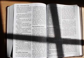 shadow as a cross on a prayer bible