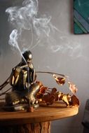 smoking incense before buddha statue on wooden table