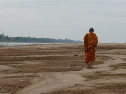 the monk in orange clothing is walking across the field