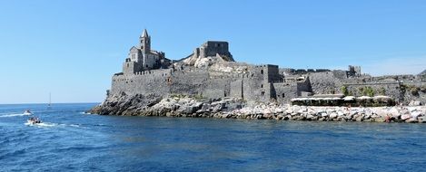 View from the sea to the castle on a rocky shore in Liguria