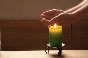 open palms near burning candle