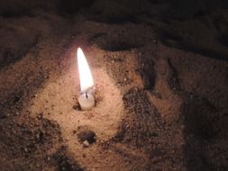 burning candle in sand