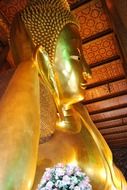 golden buddha statue with flowers, thailand