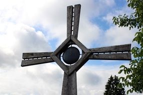 Cross with different ornaments on a cloudy sky background