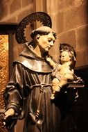 catholic saint holding baby jesus, sitting on book, sculpture