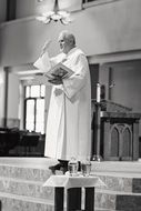 old catholic priest with bible in church