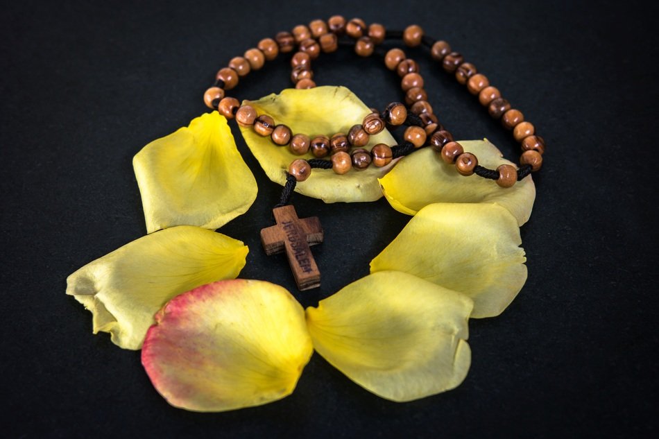 prayer chain and rose petals on black