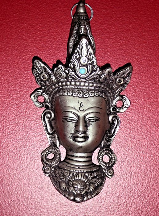pewter buddha ornament on red background