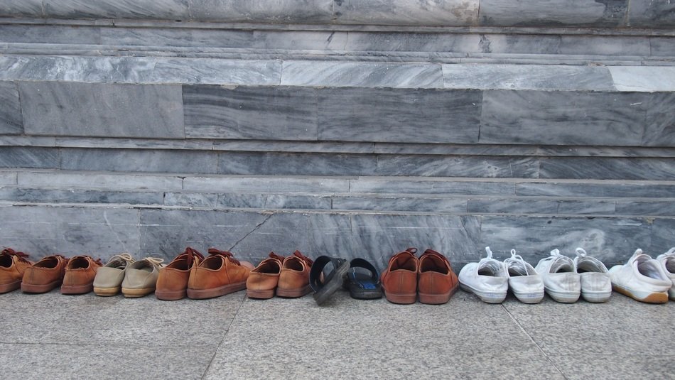 many pairs of shoes stand on the threshold of a religious building, church