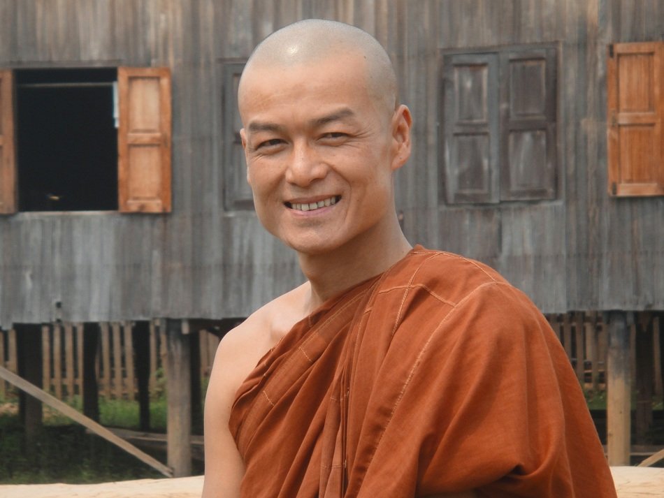 A smiling monk on the background of housing in Myanmar
