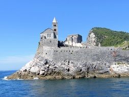 View from the water to the church on a rock in liguria