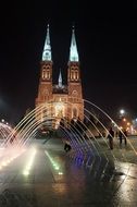 illuminated fountain in front of basilica at night