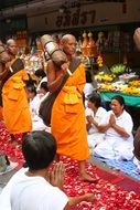 buddhists monks walking on rose petals among praying people
