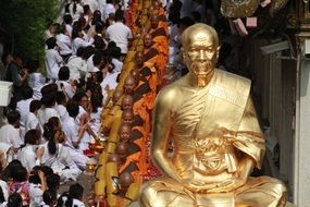 golden buddha statue on the background of monks