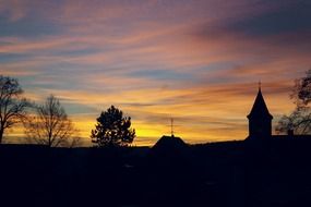 silhouette of a church and trees at sunset