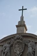 sculpture of angels with coat of arms at top of church, italy, rome