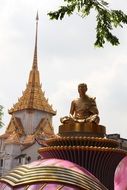 golden statue of a monk on a hill