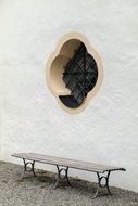 a bench stands near a wall with a window