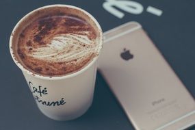 a cup of coffee next to an iphone