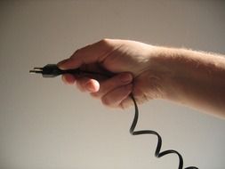 hand is holding a power cable