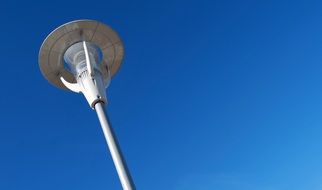 bottom view of a lamppost against a bright blue sky