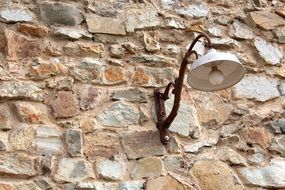 rusty street lamp on a stone wall