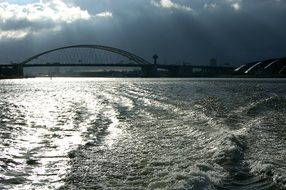 bridge across rhine river beneath stormy clouds, netherlands