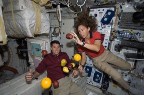 Astronauts with fruit in a state of weightlessness