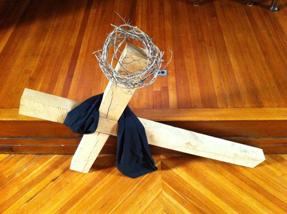 photo of a wooden cross of black fabric and a metal wreath