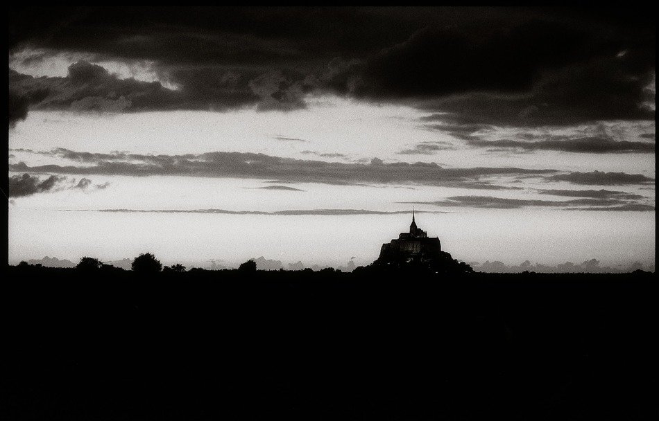 Monastery on mont st michel in the dark against a background of clouds