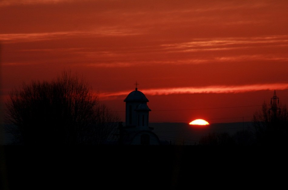 red sun sky over black silhouettes of church