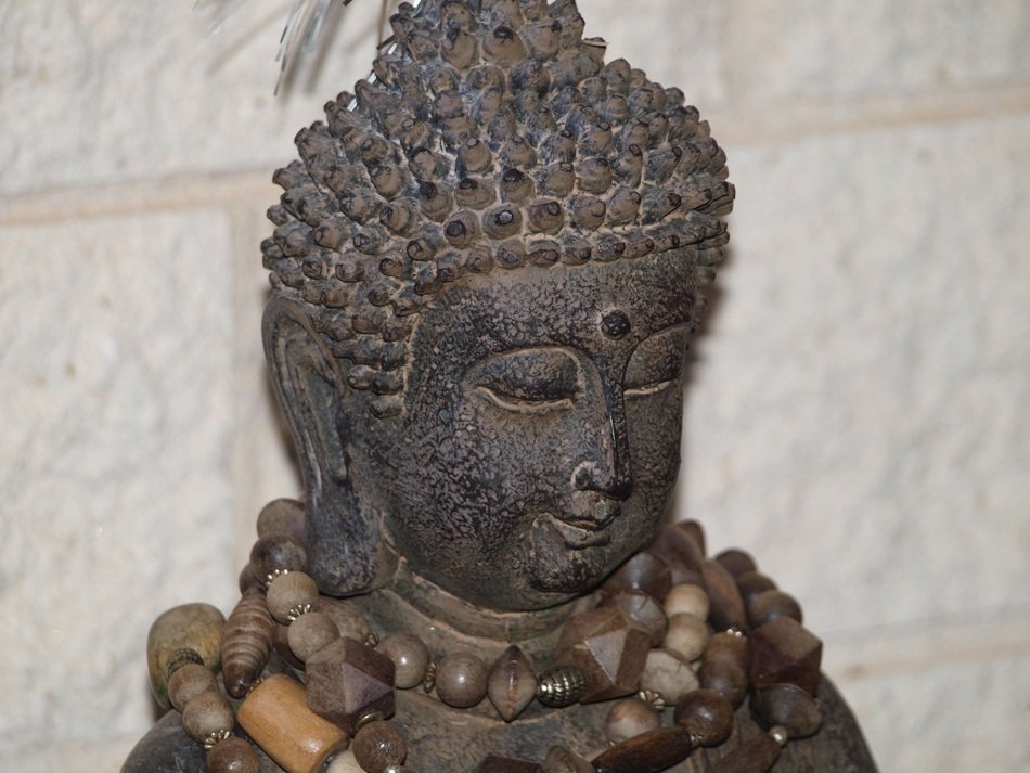 grey stone buddhist statue with beads on neck