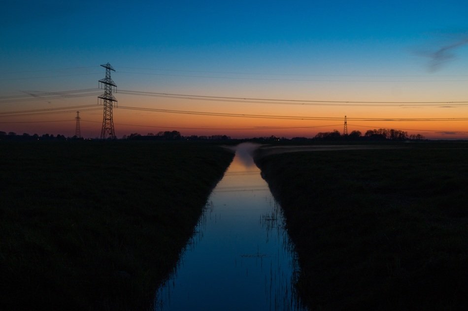 electrical wires over a stream at dusk