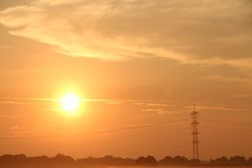 power lines pylons against an orange sunset