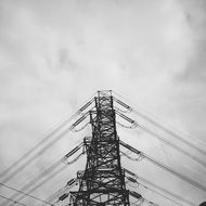 electric lines on a pillar under the sky with clouds