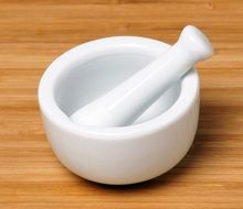 White mortar and pestle on a wooden surface