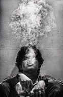 black and white photo of a smoking man near the wall