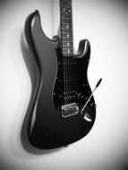black and white photo of electric guitar on a wall