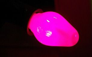 pink bulb of christmas lights in darkness