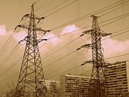 black and white photo of electric poles on the background of block city buildings