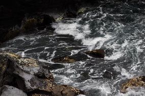 foamed dark water flow among rocks